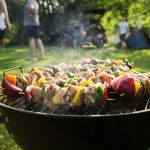 Shashlik barbecue. Wooden sticks with vegetable and meat. Chicken, pork, onion and bell pepper slices. Grilling food on a picnic. BBQ while camping with friends background. Family dinner outdoor.